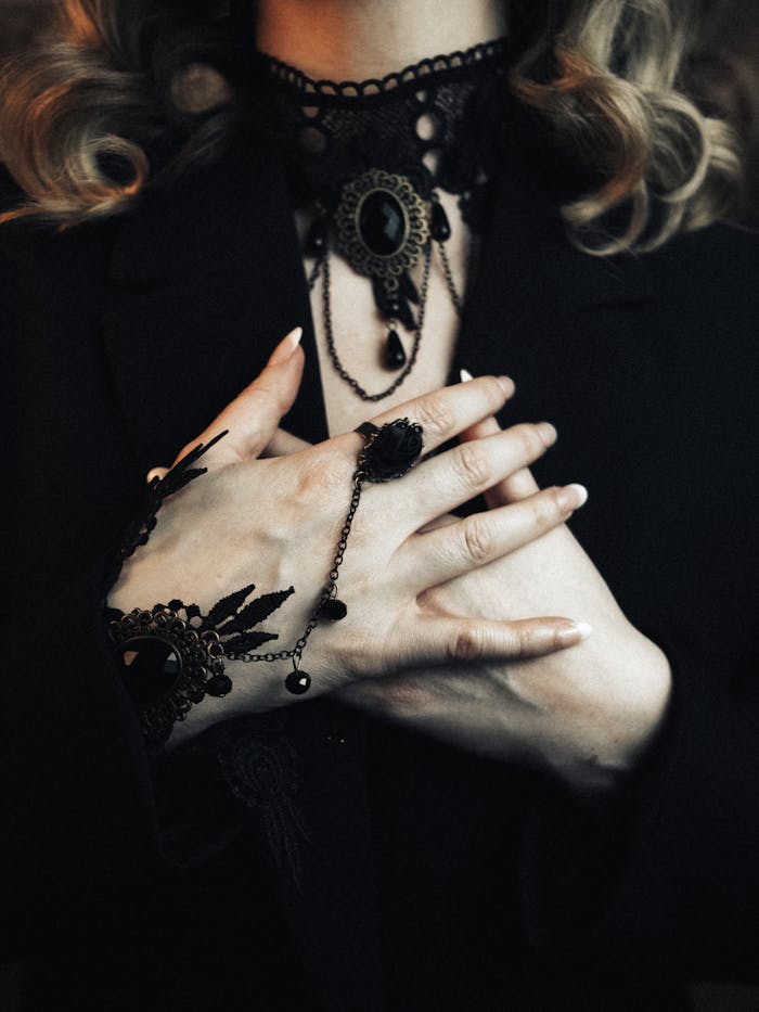 Close-up of a woman's hands adorned with intricate gothic jewelry, offering a mysterious and elegant look.