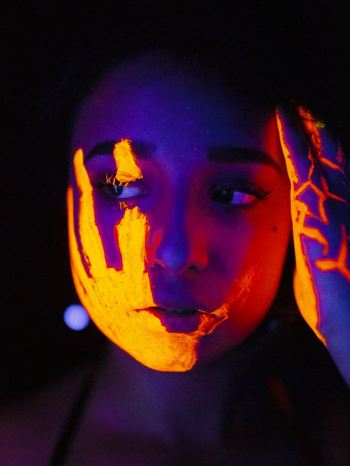 Close-up of a woman with neon face paint, creating an eerie and artistic effect.